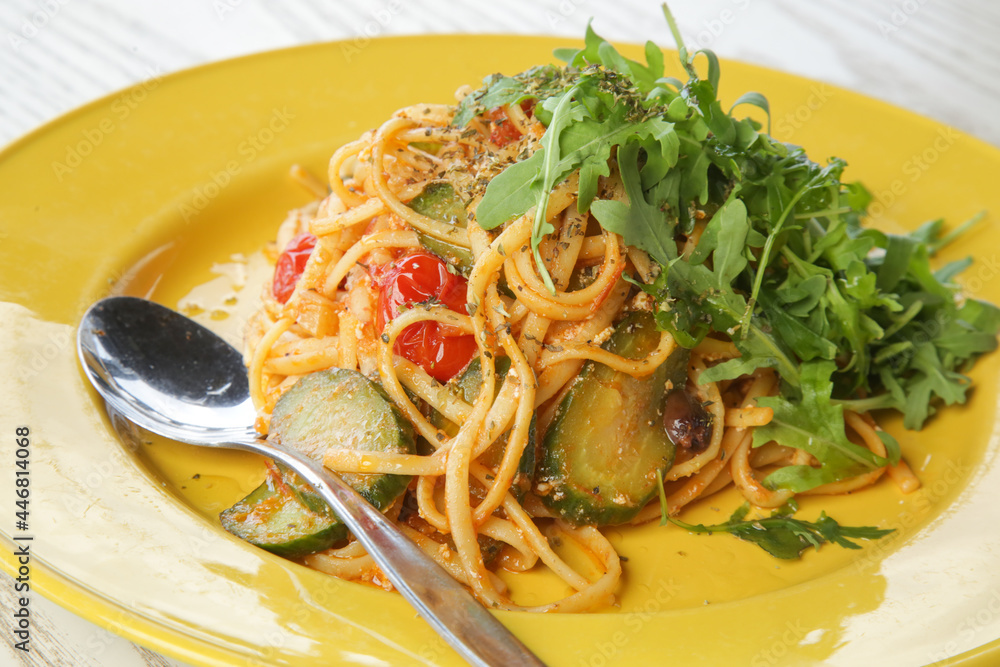 Spaghetti with vegetables and arugula served on yellow plate Spaghetti with vegetables and arugula served on yellow plate