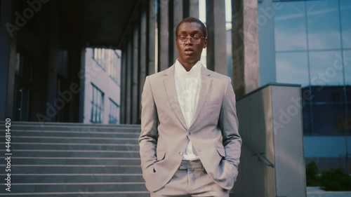 Wallpaper Mural Slow motion handsome serious young man in glasses walking on street look at camera near business center. Worker, fashion, outdoors, businessman, handsome. Close up Torontodigital.ca