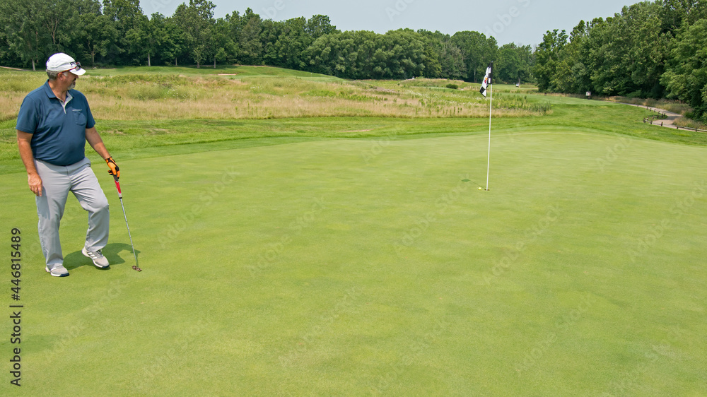 Golfer watches his putt reach very near the pin. Golfer watches his putt reach very near the pin.