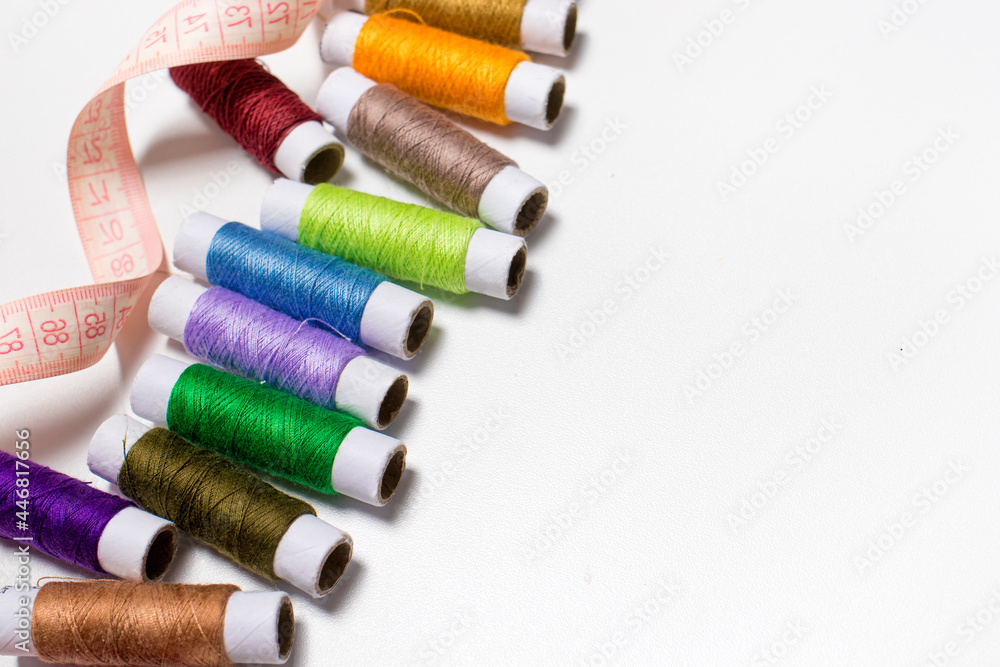 Tape measure and threads on white with space for the text of the banner. For the worker atelier, seamstress, sewing shop Tape measure and threads on white with space for the text of the banner. For the worker atelier, seamstress, sewing shop