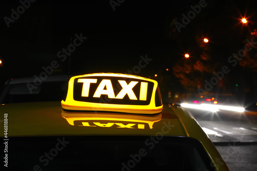 Taxi car with yellow sign on city street at night