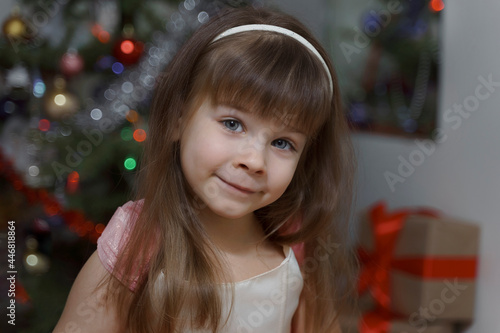 cute baby girl in a pink beautiful dress near the christmas tree