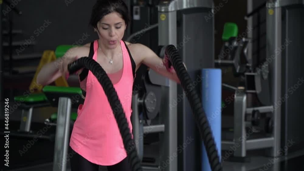 Young sportive brunette woman trains with ropes in the gym Young sportive brunette woman trains with ropes in the gym
