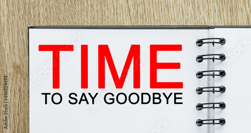 Notepad with text Time to Say Goodbye on wooden deskt. Business and finance concept photo