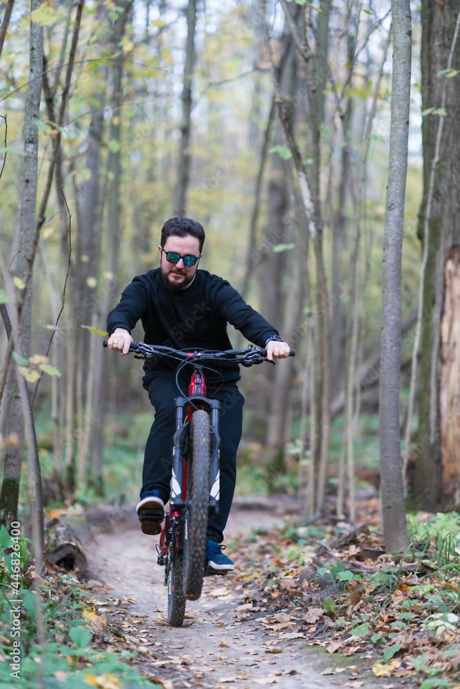 Obraz premium A man making a trick while riding a bycicle in the autumn forest
