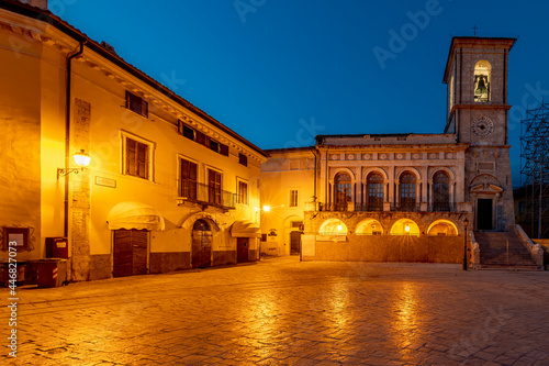 Piazza San Benedetto square in the historic center of Norcia, Italy, illuminated by evening lights