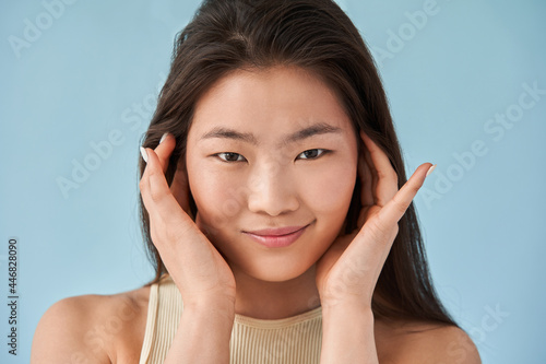 Asian long haired woman putting her hands at her face and posing