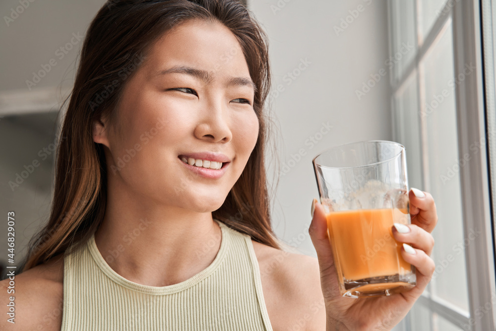 Woman looking at the window and drinking orange or carrot juice while spending her morning Woman looking at the window and drinking orange or carrot juice while spending her morning