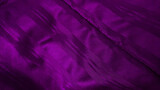 close up dark purple satiny blanket or silky fabric background with beautiful creased pattern. crumpled violet silk bed sheet background. close up purple velvet of rippled fabric.