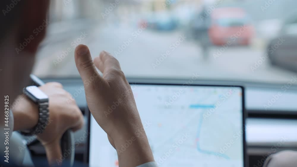 Successful businessman driving along the downtown street on high tech electric Tesla car Model 3 with male colleague nearby, man steering wheel, talking with friend, gesturing with hand on background Successful businessman driving along the downtown street on high tech electric Tesla car Model 3 with male colleague nearby, man steering wheel, talking with friend, gesturing with hand on background