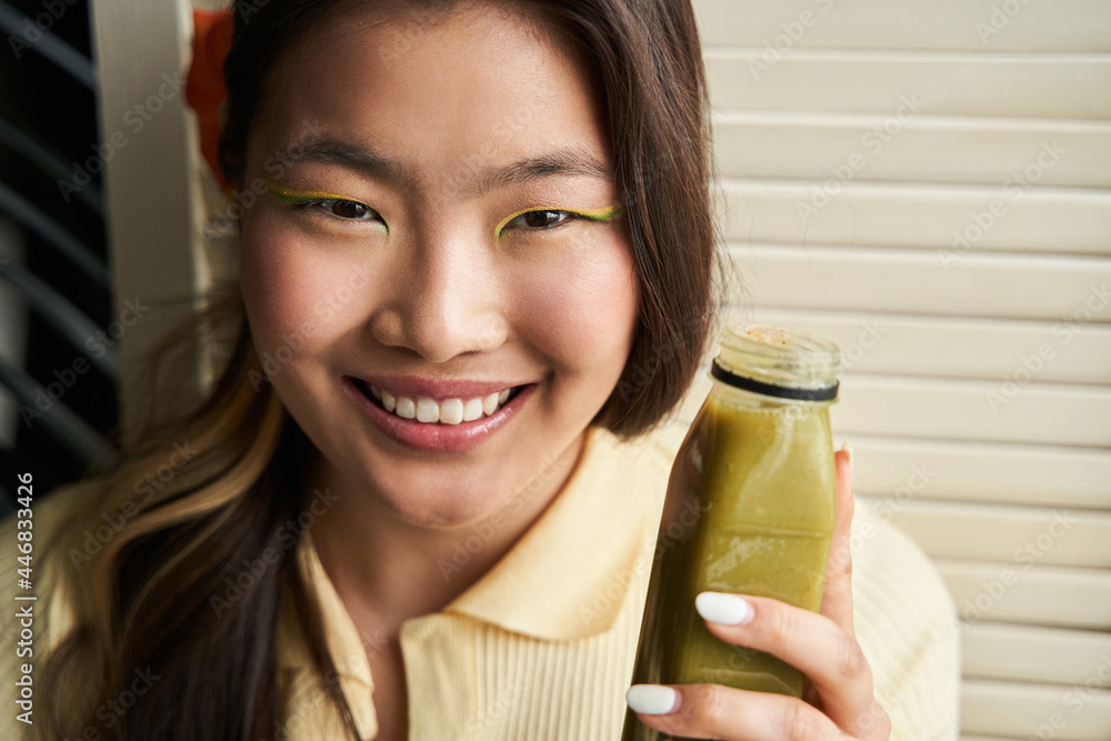 Woman looking at the camera while holding bottle of smoothie and enjoying Woman looking at the camera while holding bottle of smoothie and enjoying