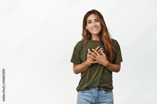 Thank you. Flattered and touched middle aged woman holding hands on chest heart, smiling pleased, grateful for smth, appreciate help, white background