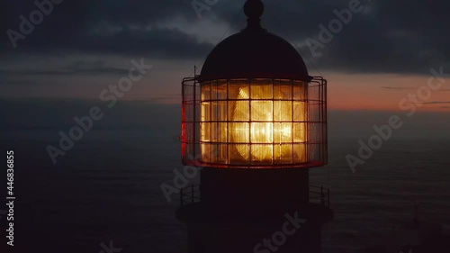 Close up of lighthouse shining head fresnel lens at dusk, drone circling around reveals sensational evening sea panorama, Lagos, Portugal photo