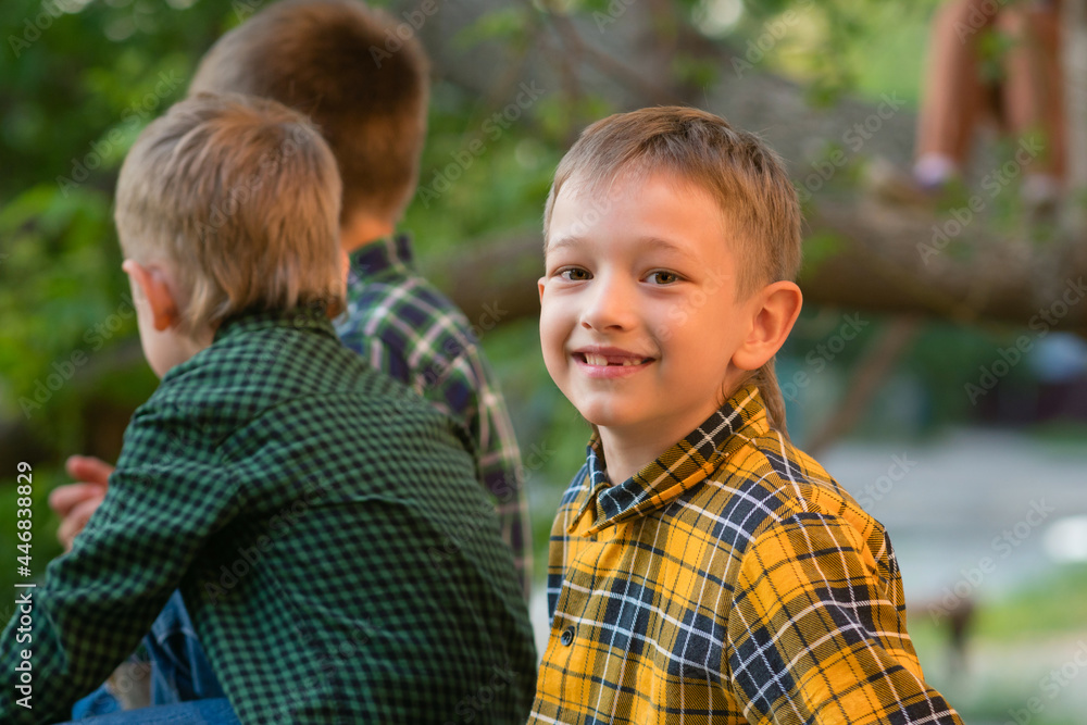 Casual three brothers relaxing in backyard. Enjoy summer vacation. Little boy looks and smiles at camera. Spend time together Casual three brothers relaxing in backyard. Enjoy summer vacation. Little boy looks and smiles at camera. Spend time together
