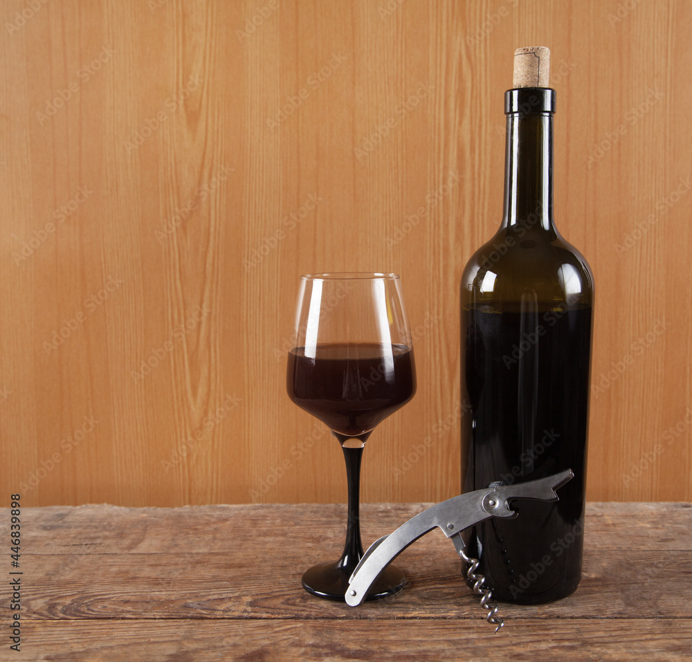 Bottle, glass and  wine with corkscrew on wooden background.