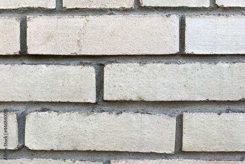 Photo of the texture of a white brick wall with gray stripes of concrete mortar