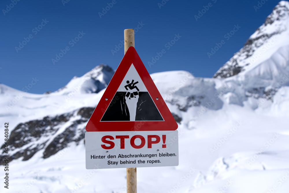 Danger sign beware of crevasse on a sunny summer day at Jungfraujoch. Photo taken July 20th, 2021, Lauterbrunnen, Switzerland. Danger sign beware of crevasse on a sunny summer day at Jungfraujoch. Photo taken July 20th, 2021, Lauterbrunnen, Switzerland.
