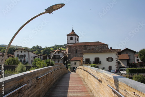 Wooden bridge that crosses a river and with the village in the background with its church in Navarre