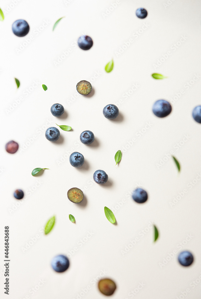 Concept flat lay with a few juicy blueberries levitation with green leaves on yellow background. Top view and close up Concept flat lay with a few juicy blueberries levitation with green leaves on yellow background. Top view and close up