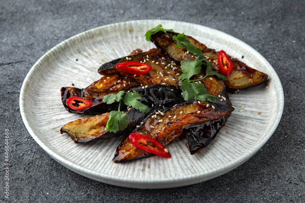 Spicy baked eggplant. Ready menu for the restaurant. Neutral gray blue textured background Spicy baked eggplant. Ready menu for the restaurant. Neutral gray blue textured background