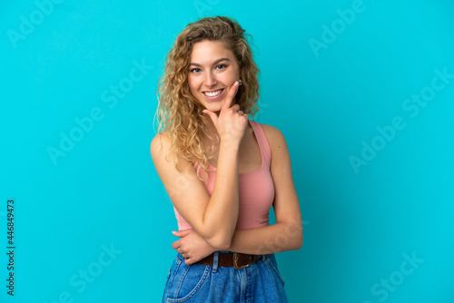 Young blonde woman isolated on blue background happy and smiling © luismolinero