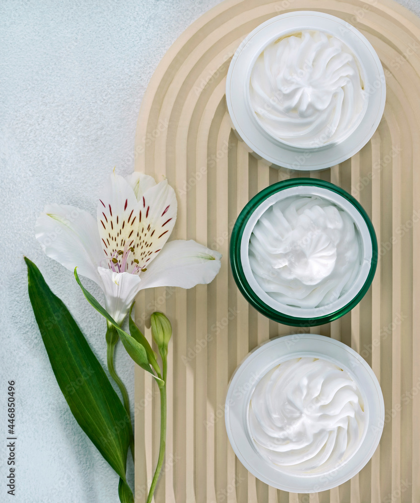 open cosmetic jars with nourishing or moisturizing cream on a corrugated beige background and alstroemeria flower open cosmetic jars with nourishing or moisturizing cream on a corrugated beige background and alstroemeria flower