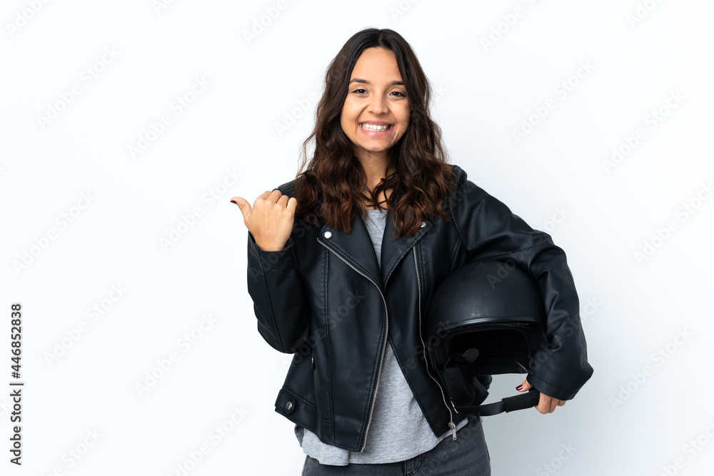 Young woman holding a motorcycle helmet over isolated white background pointing to the side to present a product Young woman holding a motorcycle helmet over isolated white background pointing to the side to present a product