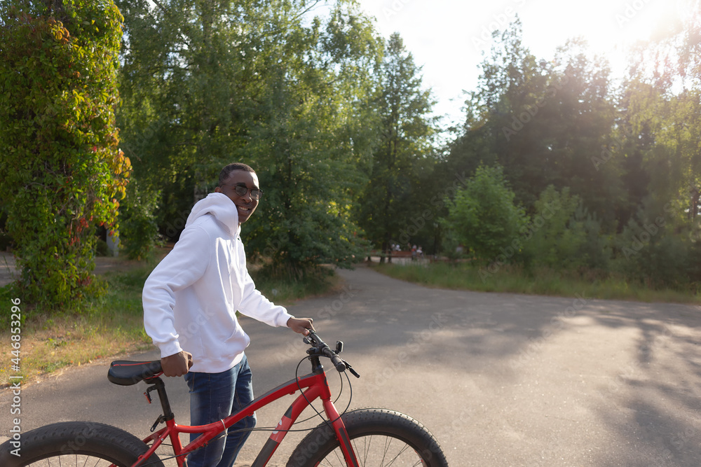 Fototapeta premium A young happy African-American man with a bicycle in nature
