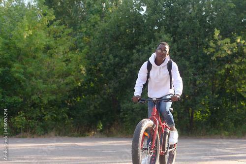 Fototapeta Naklejka Na Ścianę i Meble -  A young African-American man rides a bicycle in nature
