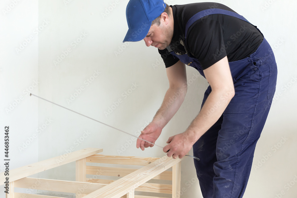 A carpenter measures a wooden structure. Carpentry work