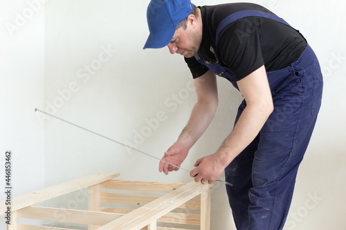 A carpenter measures a wooden structure. Carpentry work © Alexander