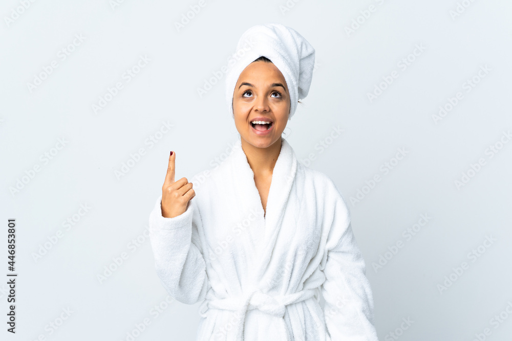 Young woman in bathrobe over isolated white background pointing up and surprised Young woman in bathrobe over isolated white background pointing up and surprised