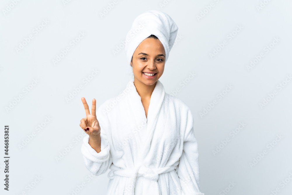 Young woman in bathrobe over isolated white background smiling and showing victory sign Young woman in bathrobe over isolated white background smiling and showing victory sign
