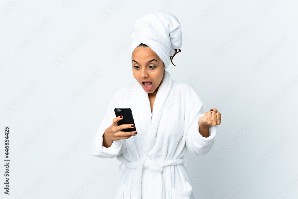 Young woman in bathrobe over isolated white background surprised and sending a message Young woman in bathrobe over isolated white background surprised and sending a message