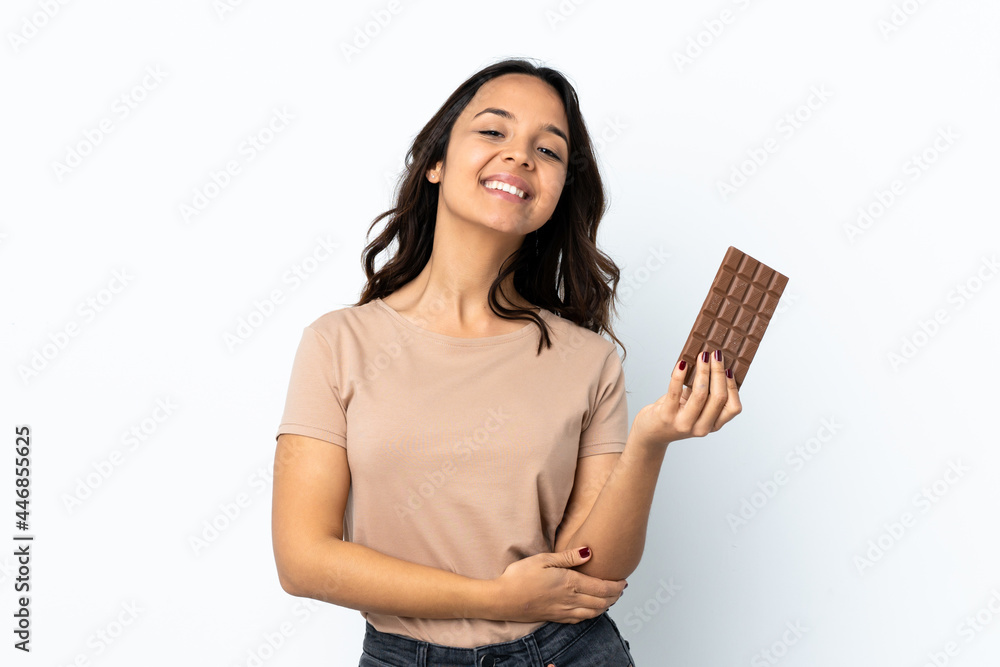 Young woman over isolated white background taking a chocolate tablet and happy Young woman over isolated white background taking a chocolate tablet and happy