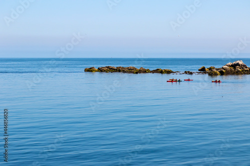 Photography Kayakers in colorful boats kayaks enjoy leisure activity on calm blue waters of Irish Sea