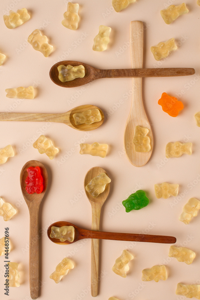 gummies bears composition with wooden spoons. brown background gummies bears composition with wooden spoons. brown background