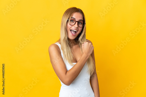 Young blonde woman isolated on yellow background celebrating a victory © luismolinero