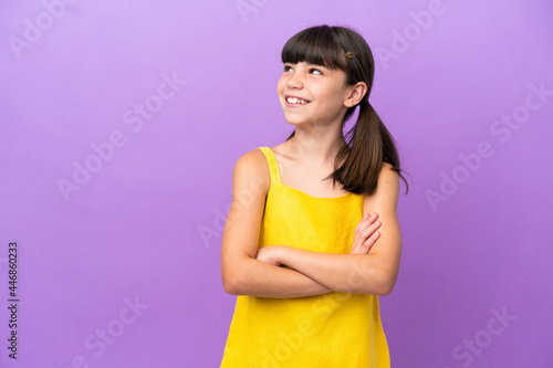 Little caucasian kid isolated on purple background looking to the side