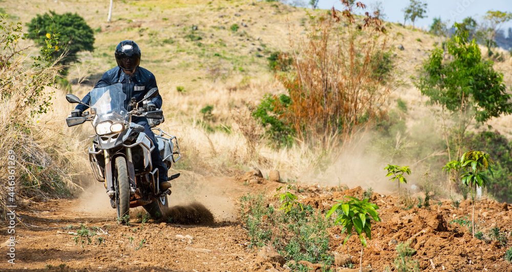 Man riding his adventure motorbike on dirt road in Cambodia Man riding his adventure motorbike on dirt road in Cambodia