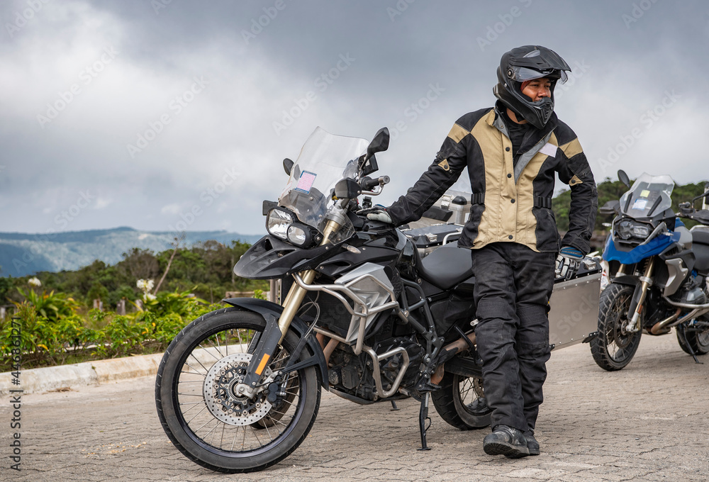 man standing next to his adventure motorbike on road trip in Cambodia man standing next to his adventure motorbike on road trip in Cambodia