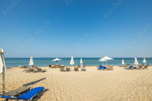 Landscape view of empty sunbeds under umbrellas on sand beach. Greece.  © Alex