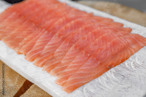 Sliced red fish is lying on a wooden tray.