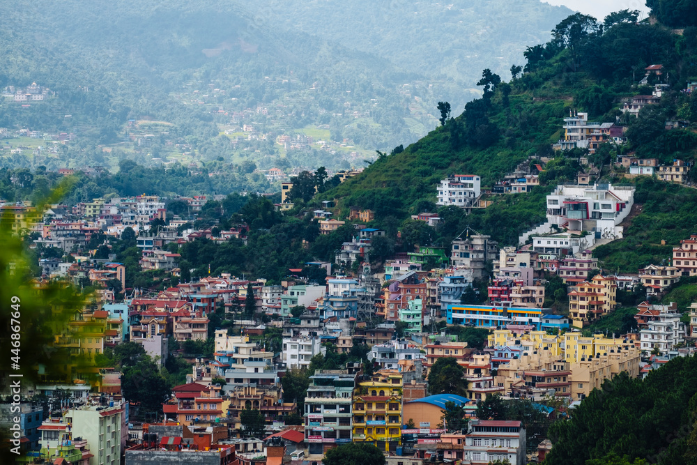 Colourful cityscape infrastructure housing of Kathmandu against mountains in Nepal during early morning light.