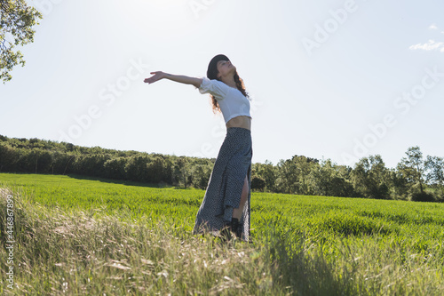woman with hat in a wheat field against the sun