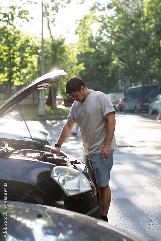 a man on a city street checks the operation of the car, looks under th