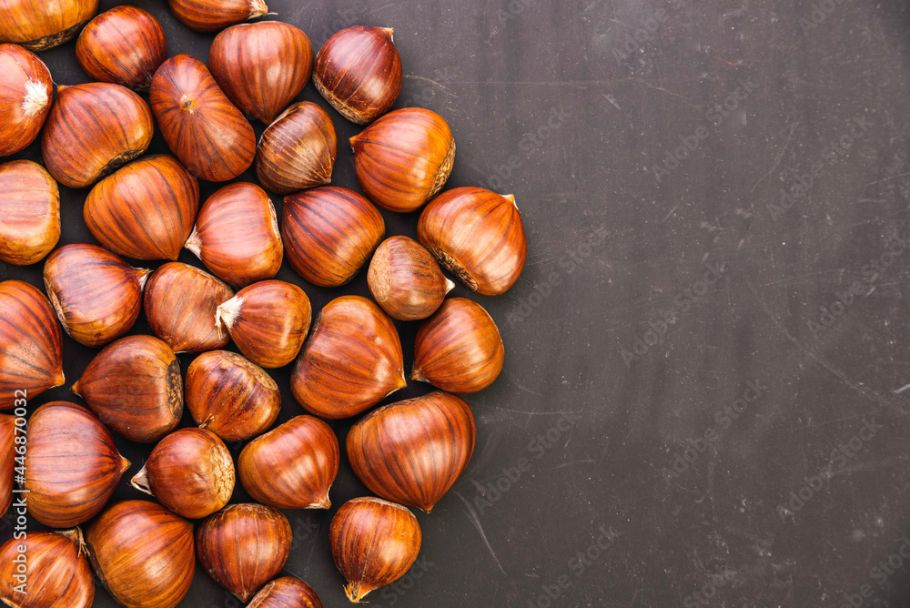 Obraz premium Ripe chestnuts close up. Raw Chestnuts for Christmas. Fresh sweet chestnut.