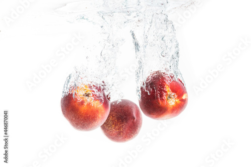Nectarine fruits splashing into water and sinking