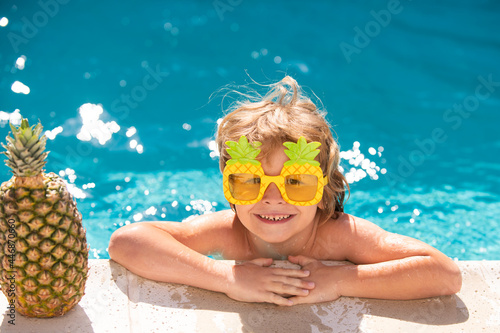 Children play in tropical resort. Child boy and best swimming pool. Cute kid relaxing on swimming pool. Summer pineapple fruit.