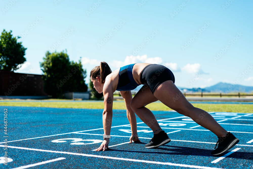 Woman athlete on running field in starting position Woman athlete on running field in starting position